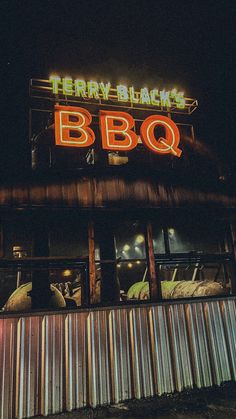 there is a bbq sign lit up on the side of this building at night