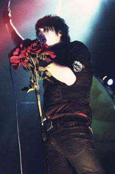 a man holding a red rose on stage