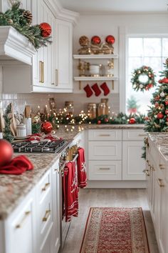 a kitchen decorated for christmas with white cabinets and red ornaments on the countertops, along with garlands