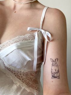 a woman with a rabbit tattoo on her left arm and right arm behind her shoulder