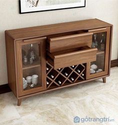 a wooden cabinet with wine bottles and glasses in it next to a painting on the wall