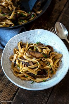 pasta with mushrooms and parmesan cheese in a white bowl on a wooden table