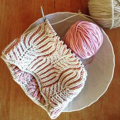 two balls of yarn sitting on top of a plate next to a ball of yarn