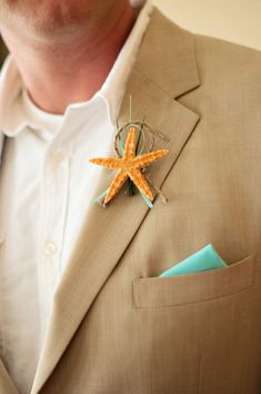 a man in a suit and tie is wearing a starfish brooch on his lapel