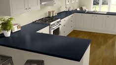 a large kitchen with white cabinets and black counter tops, along with two stools