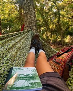 a person laying in a hammock reading a book