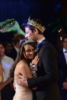 a man in a tuxedo hugging a woman wearing a tiara at a party