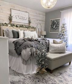 a bedroom decorated for christmas with white and gray decor, silver accents and greenery