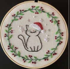 a white cat with a santa hat on it's head is sitting in a wreath