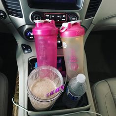 two blenders are sitting in the center console of a car, next to an empty cup