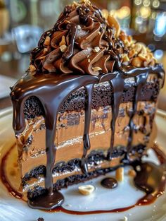 a piece of chocolate cake on a white plate with drizzled chocolate and nuts