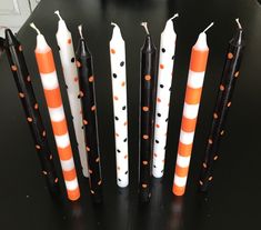 five candles with orange and white polka dots are lined up on a black table top