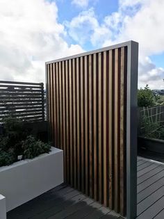 a wooden slatted wall next to a white planter on a roof deck