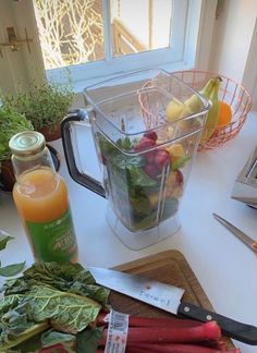 vegetables and fruit on a cutting board next to a blender with juice in it