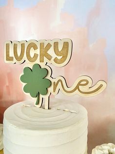 a white cake with a wooden lucky one sign on top