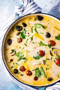 a pot filled with soup and topped with tomatoes, olives, parsley and cilantro