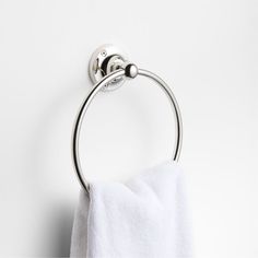 a towel hanging on the wall next to a toilet paper roll and a metal ring