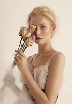 a woman holding three flowers in her hands