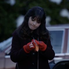 a woman standing in front of a car while holding onto a piece of food that is being held by her hands