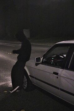 a person standing next to a parked car in the dark