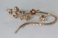 This gorgeous ear cuff is decorated with a variety of leaves and flowers, including one rose and a single swarovsky crystal. It comes with a small leaf stud for the other ear. There are two chains that fall from the lower corner of the cuff and go just beyond the chin level. You only need one piercing at the bottom of the ear in order to wear this ear cuff. The top part of the cuff could easily be adjusted to fit any ear size with a small screw that easily makes it tighter or looser and does not Dainty Gold Ear Cuff For Wedding, Gold Dangle Ear Cuff For Wedding, Elegant Flower Shaped Ear Cuff As Gift, Elegant Rose Gold Ear Cuff For Wedding, Bohemian Ear Cuff For Weddings With Pierced Ears, Adjustable Dangle Ear Cuff For Wedding, Rose Gold Ear Cuff For Wedding, Elegant Bridal Jewelry, Bohemian Wedding Jewelry