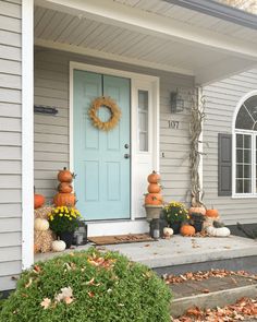 a front porch decorated for fall with pumpkins and gourds