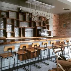 an empty bar with wooden chairs and shelves filled with wine glasses on the back wall