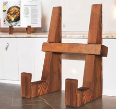 two wooden letters sitting on top of a counter next to a book holder and an open cookbook