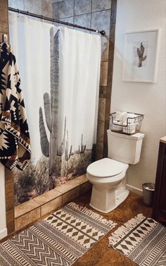 a bathroom with a cactus shower curtain next to a toilet and rug on the floor