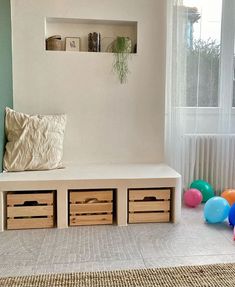 a living room with balloons on the floor and a bench in front of a window