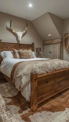 a bedroom with a bed, dresser and cow skull head on the wall above it