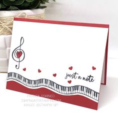 a card with music notes and hearts on it, sitting next to a potted plant