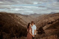 a man and woman standing on top of a mountain