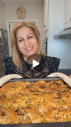 a woman is holding up a large tray of bread in the kitchen with sprinkles on it