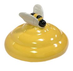 a yellow and black bee figurine sitting on top of a white surface with its head turned to the side