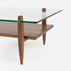 a glass and wood coffee table with two legs on each side, against a white background