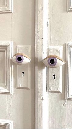 the door is painted white and has two fake eyes on it, as well as a keyhole