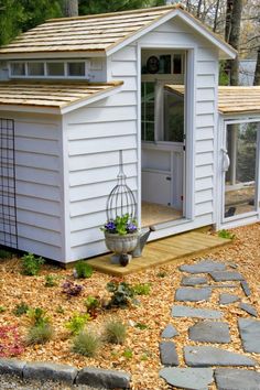 a small white shed sitting in the middle of a yard next to a stone walkway