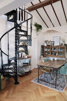 a spiral staircase in the middle of a living room next to a table and chairs