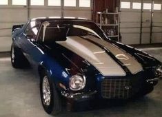 a blue and white muscle car parked in a garage