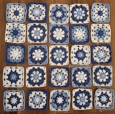 blue and white crocheted squares are arranged in rows on a wooden table top