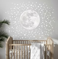 a baby's crib in front of a wall with stars and the moon