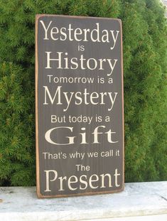 a wooden sign that says, yesterday is history tomorrow is a mystery but today is a gift that's why we call it the present