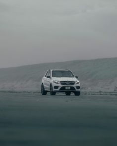 a white car parked on the side of a road in front of a large hill