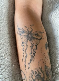 a close up of a person's leg with tattoos on it and a butterfly