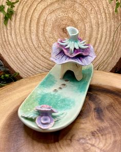 a ceramic figurine sitting on top of a wooden table next to a plant