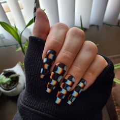 a woman with black and orange nail polish holding up her hand in front of the camera