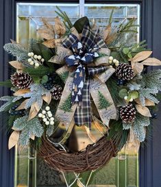 a wreath with pine cones and evergreens on the front door is adorned with a plaid bow