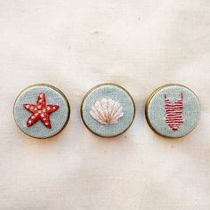 three different types of buttons with shells and starfishs in them on a white surface