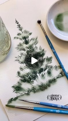 watercolors and paintbrushes are sitting on a table next to a painting